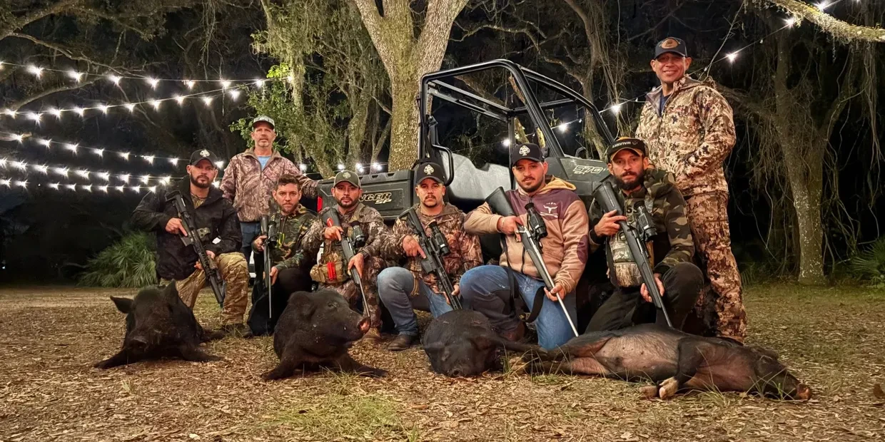 Group of hunters posing after a successful nighttime hog hunt